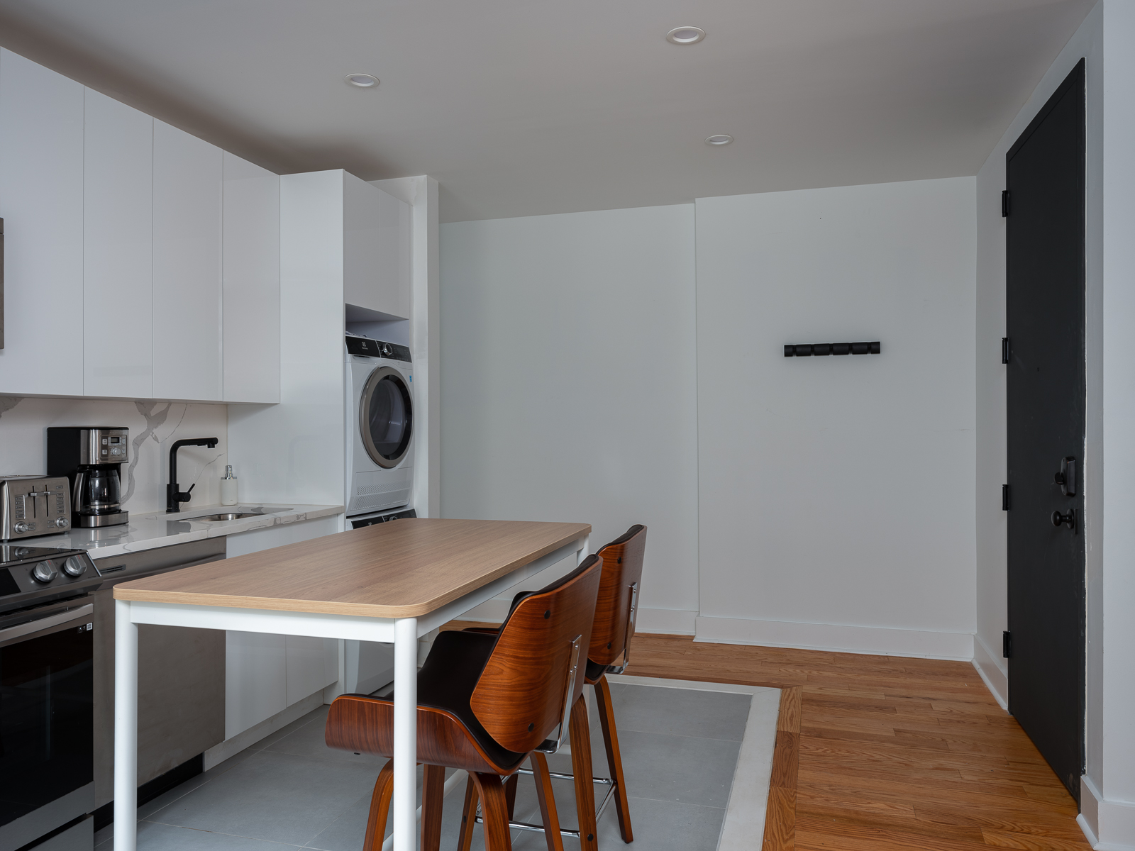 Entry with black front door, wall hooks and kitchen island