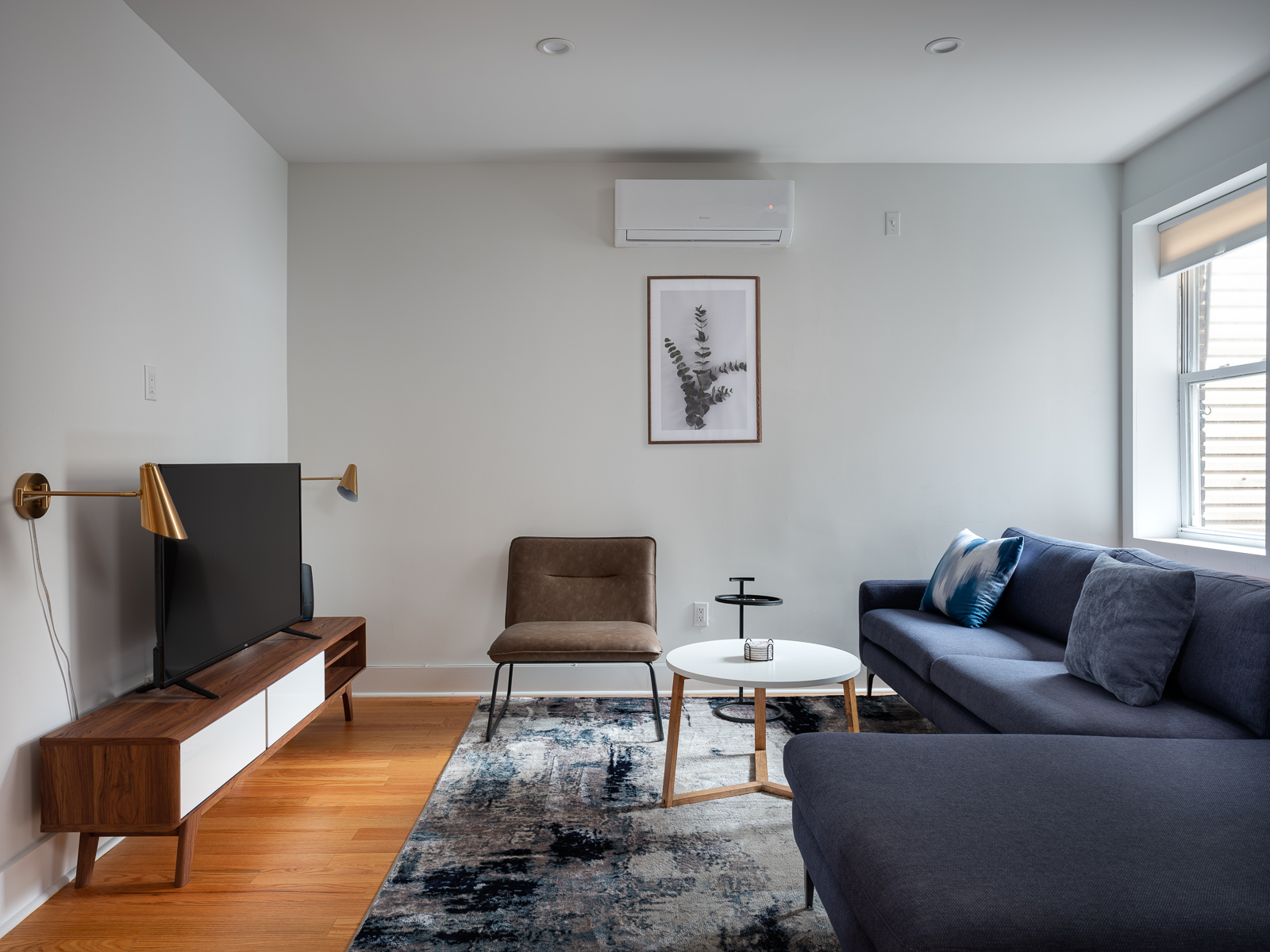 Living room with navy sectional, leather chair and walnut media console
